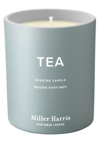 Duftkerze in einem matt hellgrauen Behälter mit weißem Text, der das Wort "TEA" zeigt, sowie dem Markennamen "Miller Harris" am Boden.