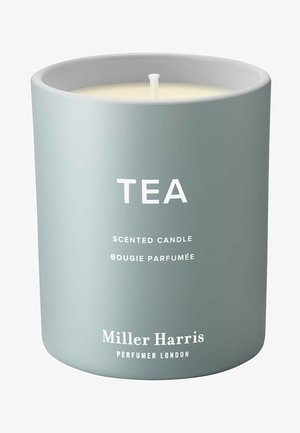 Duftkerze in einem matt hellgrauen Behälter mit weißem Text, der das Wort "TEA" zeigt, sowie dem Markennamen "Miller Harris" am Boden.