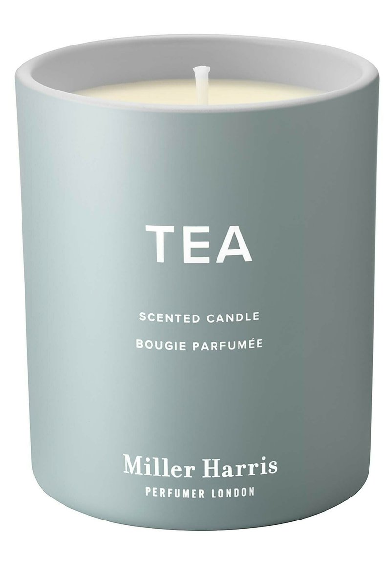 Duftkerze in einem matt hellgrauen Behälter mit weißem Text, der das Wort "TEA" zeigt, sowie dem Markennamen "Miller Harris" am Boden.
