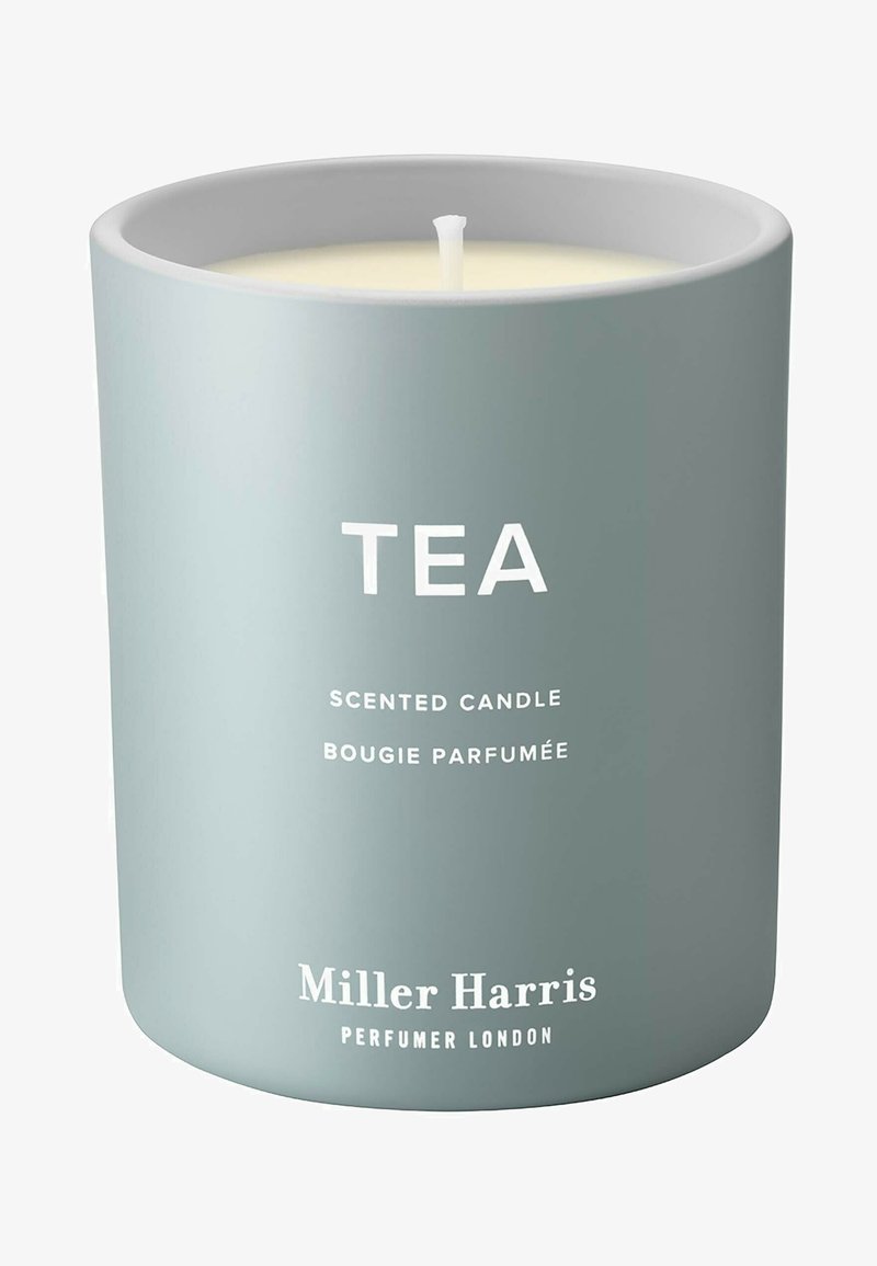 Duftkerze in einem matt hellgrauen Behälter mit weißem Text, der das Wort "TEA" zeigt, sowie dem Markennamen "Miller Harris" am Boden.