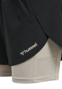Svarta shorts med ett beige innerlager, med en framträdande Hummel-logotyp och kontrasterande sömmar. Slätt tyg med en lätt design.