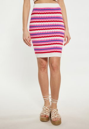 Gebreide kokerrok met zigzagpatronen in roze, rood en blauw, gecombineerd met tan espadrillesandalen met vetersluiting en een gevlochten basis.