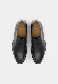 Black leather dress shoes with a smooth finish, lace-up design, rounded toe, and brown insole labeled "BOSS, Made in Italy."
