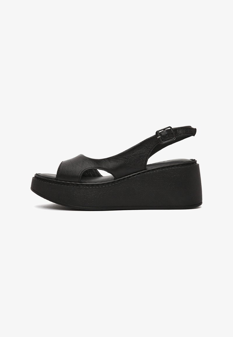 Sandale compensée en cuir noir avec bout ouvert, bride cheville ajustable et semelle plateforme épaisse.