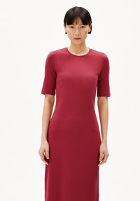 Rode, geribbelde midi-jurk met korte mouwen, ronde halslijn en een slim fit. De stof heeft een zachte textuur met subtiele patroondetails.