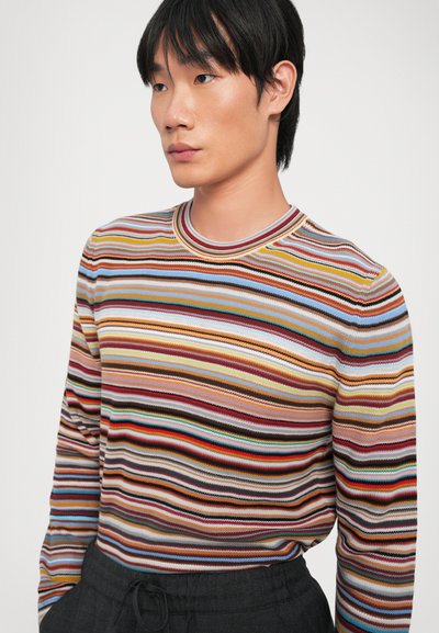 Chemise à manches longues rayée multicolore avec un col rond, présentant des lignes horizontales dans des teintes de rouge, bleu, jaune et marron. Tissu tricoté texturé.