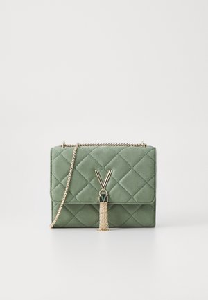 Pikowana zielona torebka z złotym łańcuszkiem i frędzlem, zawieszona na złotym zatrzasku w kształcie litery V na przedniej klapie.