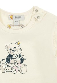 Cream-colored cotton onesie with snap closures, featuring a printed design of a teddy bear and a dalmatian on the front.