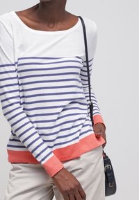 Paski długi rękaw w białym i granatowym kolorze, z koralowymi akcentami na mankietach i u dołu. Miękki materiał, dekolt typu łódka i luźny krój.