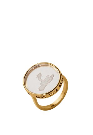Anillo de oro con parte superior redonda y translúcida que presenta una figura blanca esculpida en su interior y texto grabado "MAY THE STARS" alrededor del borde.