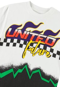 Balta medvilninė marškinėliai, kuriuose ryškūs „UNITED“ ir „ateitis“ grafikai raudona, purpurine ir geltona spalvomis, o apatiniame krašte – žalias zigzago raštas.