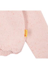 Světle růžový pletený svetr s texturovaným vzorem a barevnými flíčky, se žlutou značkovou štítkem na boku.