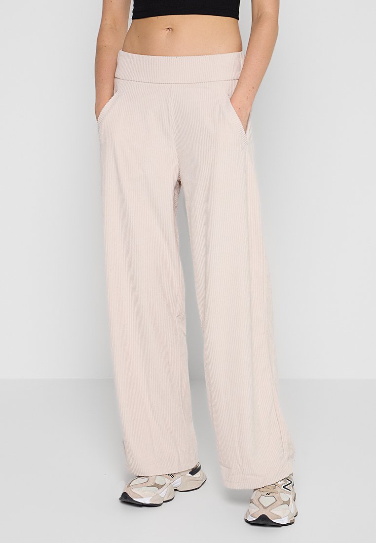 Pantaloni in corduroy beige chiaro con un design a gamba larga, dotati di tasche laterali e una cintura elastica comoda.