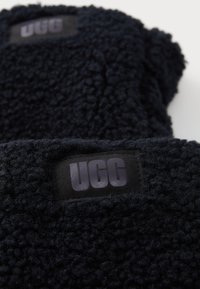 Dark navy fleece blankets with a textured surface, featuring a black fabric label with "UGG" in stylized lettering.