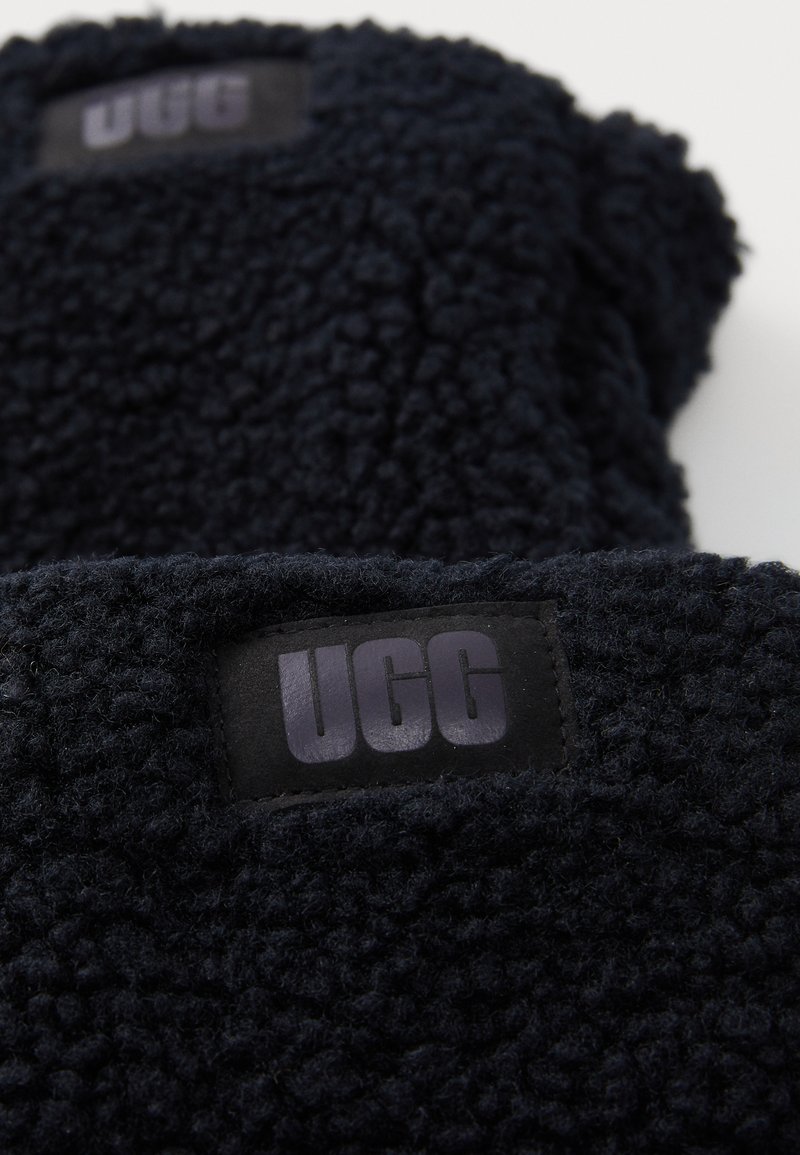 Couvertures en polaire bleu marine foncé avec une surface texturée, dotées d'une étiquette en tissu noir avec "UGG" en lettres stylisées.