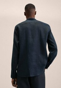 Camicia di lino blu scuro con maniche lunghe, colletto a punta e polsini con bottoni. Tessuto morbido e vestibilità casual.