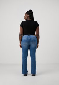 Black short-sleeve top paired with blue flared jeans featuring back pockets and a leather tag on the waistband. Simple, casual design.