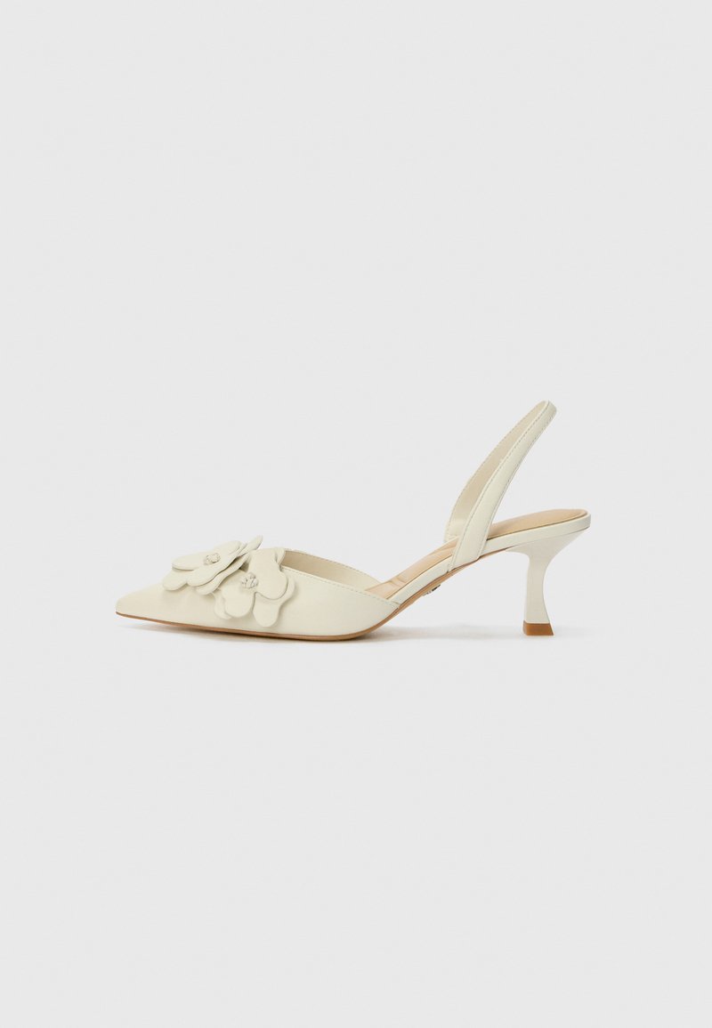 Talons slingbacks de couleur crème avec un bout pointu, des embellissements floraux sur le devant et un talon fin et courbé.