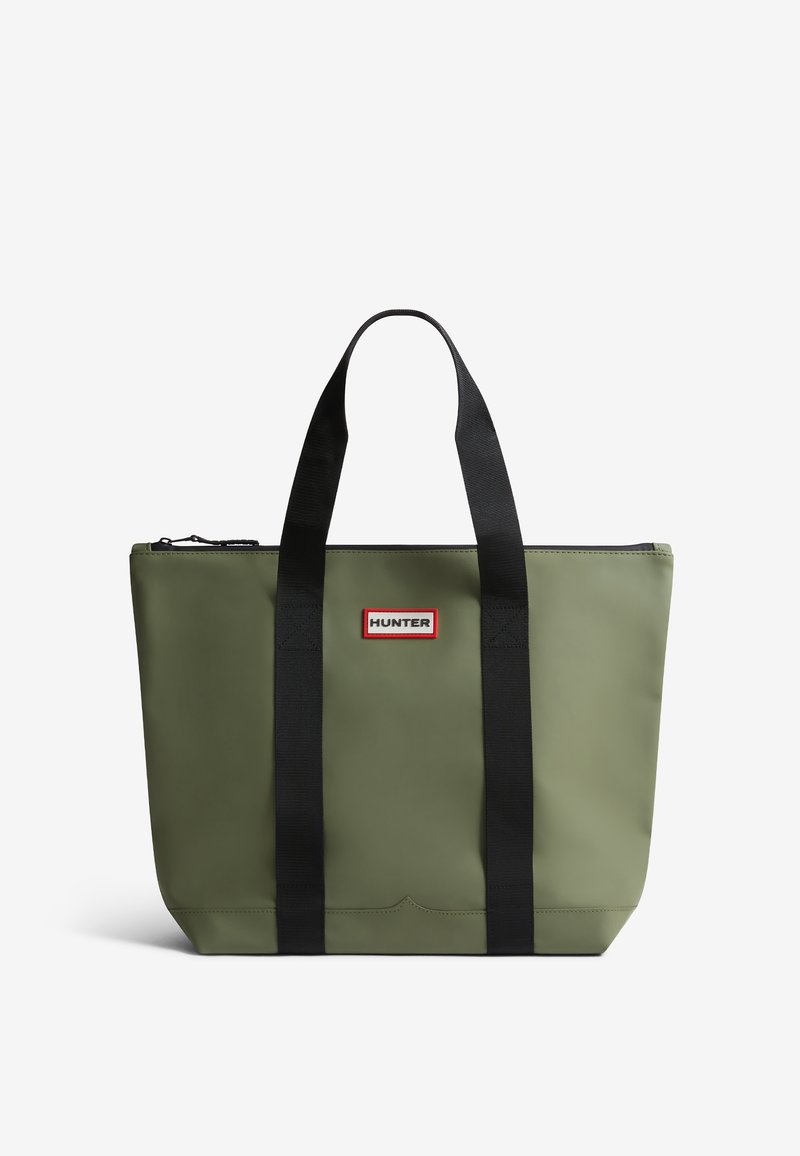 Green waterproof tote bag with black straps, zip closure, and a red and white logo patch on the front. Smooth texture, rectangular shape.