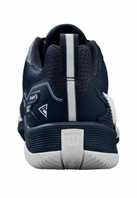 Zapatilla deportiva en color azul marino con una parte superior de malla texturizada, una franja blanca en el talón, suela de goma y logotipo visible de la marca en la parte posterior.