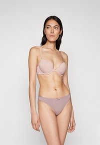 Lichtroze, gevoerde bh met verstelbare bandjes, gecombineerd met bijpassende bikinislips met een lage taille en een verfijnde strikdetails op de tailleband.