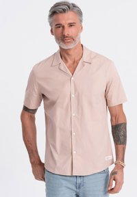 Lichtroze korte mouw button-up shirt gemaakt van gladde katoen, met een uitgesneden kraag en witte knopen, gedragen met lichtblauwe spijkerbroek.