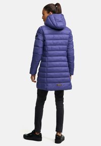 Vadderad lila jacka med huva, med horisontella sömmar, en stilren design och en märkesetikett i fållen. Matchas med svarta byxor.