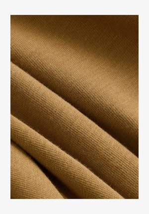 Tessuto morbido e strutturato di un caldo colore senape, che presenta eleganti motivi a maglia con sottili variazioni di tono e una caduta fluida.