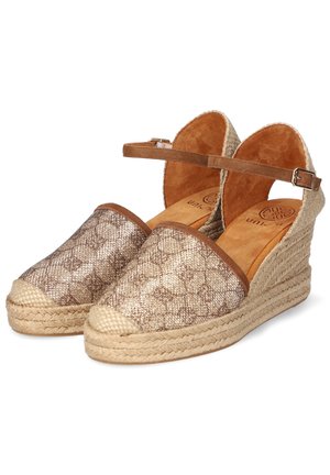 Sandały espadryle na klinie z beżową plecioną platformą, wzorzystym zamkniętym przodem oraz brązowym paskiem wokół kostki z klamrą.