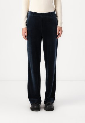 Pantaloni in velluto blu navy con un design a gamba dritta, dotati di tasche frontali e una superficie morbida, abbinati a scarpe nere.