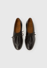 Μαύρα δερμάτινα παπούτσια με υφή, στρογγυλή μύτη και σχέδιο με κορδόνια. Στο εσωτερικό διαθέτουν ταμπά δερμάτινο πάτο με σήμανση.