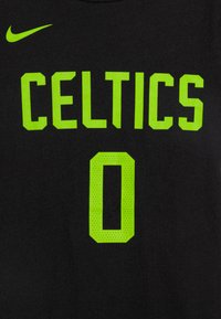 T-shirt en coton noir avec un grand texte vert fluo qui indique "CELTICS" et un numéro "0" vert en dessous, avec une texture lisse.
