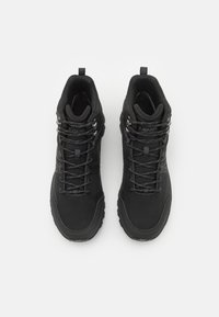 Botas de senderismo negras con parte superior sintética, que cuentan con cordones, ganchos de metal y una suela de goma texturizada para mayor tracción.