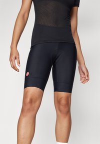 Sorte sykkelshorts laget av elastisk stoff. Har en tettsittende passform, kontrast med rød logo, og et polstret innlegg for komfort under sykling.