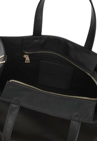 Intérieur d'un sac fourre-tout en cuir noir avec une poche zippée, des accessoires en or, une étiquette embossée et une texture lisse. Bandes en tissu solides incluses.