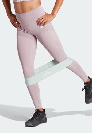 Leggings lilas clairs en tissu extensible, avec une large taille et une bande de résistance vert clair contrastante autour des cuisses.