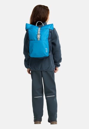 Zaino blu a sacco con una tracolla grigia, tasca laterale in rete e tasca frontale aggiuntiva, realizzato in materiale resistente, indossato da un bambino.