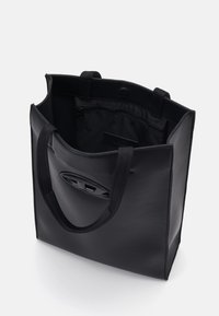 Sac fourre-tout noir avec deux poignées, en matière synthétique lisse. Intérieur comprenant une poche zippée et un logo intérieur. Forme rectangulaire simple.