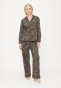 Pysjamasett med leopardmønster i myk stoff; langermet knappeskjorte med lomme og matchende rette bukser. Jordfarger.