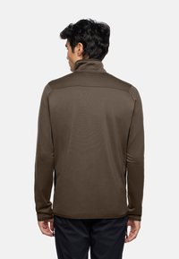 Brauner Pullover mit langen Ärmeln und hohem Kragen, strukturiertem Stoff, schwarzen Seitenpaneelen und slim fit. Die Rückansicht zeigt klare Linien und keine Verzierungen.