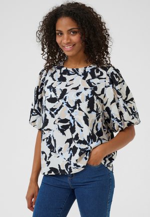 Blouse ample en tissu léger, avec un motif abstrait noir et bleu clair, des manches courtes bouffantes et un col rond.