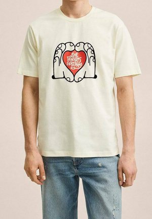 Jasnożółta koszulka z krótkim rękawem z grafiką rąk tworzących serce oraz czerwonym napisem "Miłość wszystko zmienia."