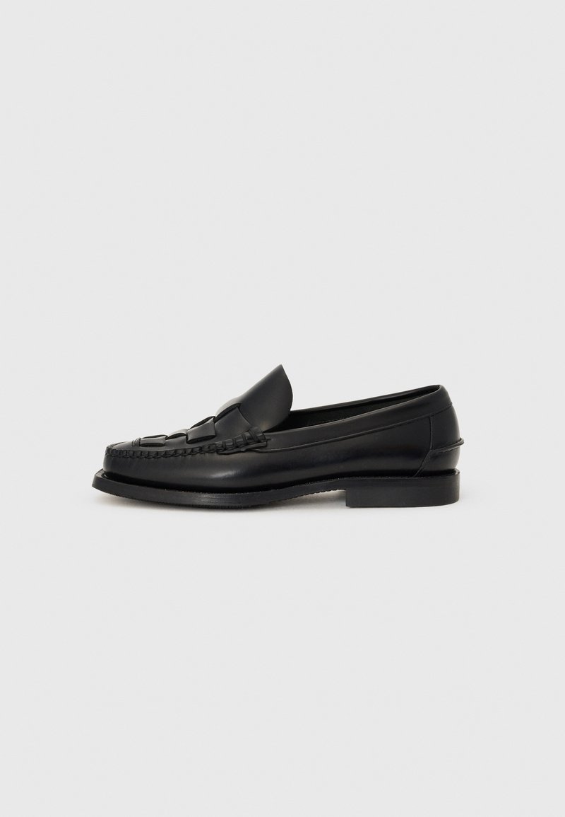Mocassin en cuir noir avec un détail tissé à l'avant, bout arrondi et petit talon. Texture lisse et design minimaliste.