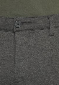 Pantalon gris avec une texture lisse, fermeture éclair, et un seul bouton noir au niveau de la taille. Design uni sans motifs visibles.