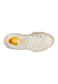 Vit sneaker med en texturerad kanvasöverdel, gummitåhette och kontrasterande gul innersula. Har tunna snören och spetsig sula f ör bättre grepp.