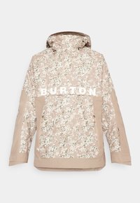 Beige camouflagejakke med hætte, der har "BURTON" i fede hvide bogstaver, lynlåslomme foran og struktureret stof til udendørs brug.