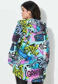 Barevná bunda s kapucí s graffiti vzorem, převážně v modré, růžové, žluté a černé barvě. Vyrobena z látky s hladkým povrchem.