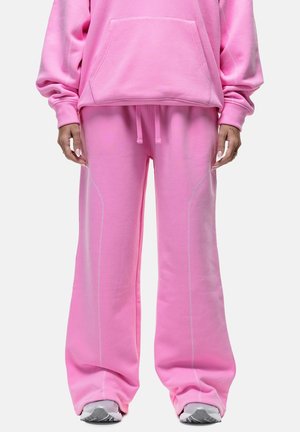 Roze sweatshirt en bijpassende wijdvallende broek van zachte stof, met witte stiksels langs de naden en een verstelbare tailleband.