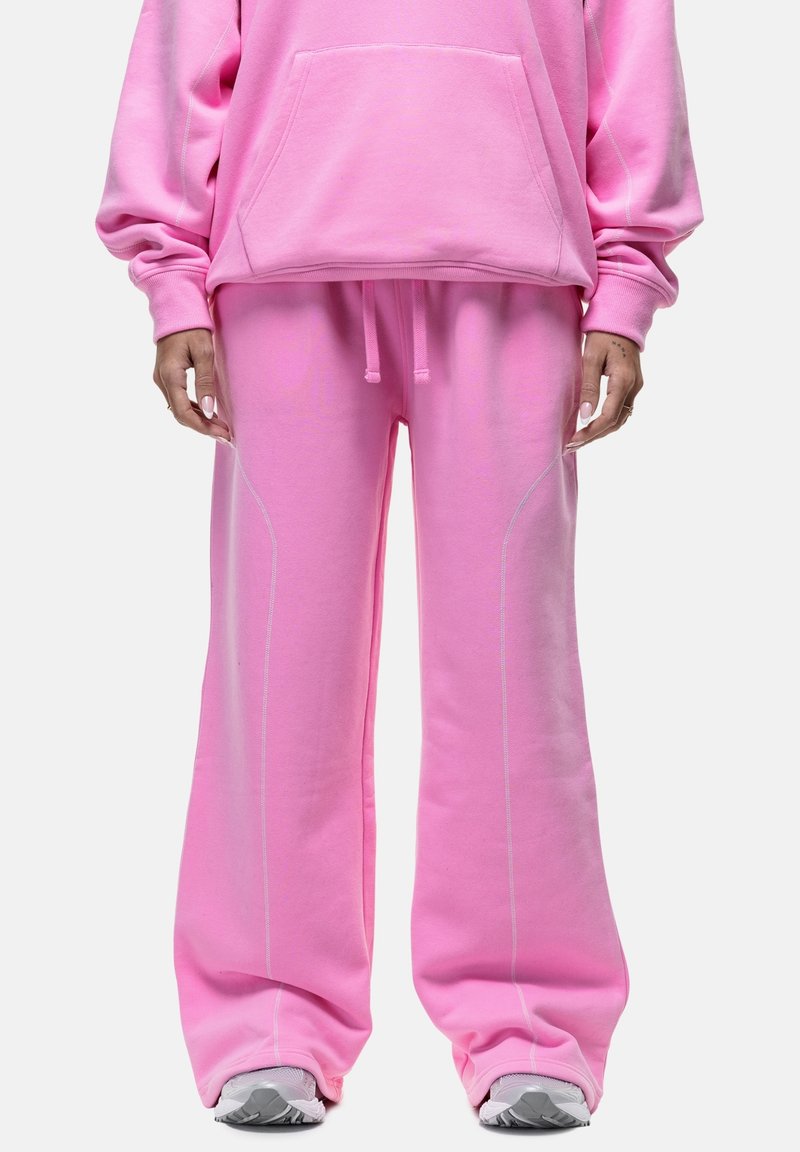 Roze sweatshirt en bijpassende wijdvallende broek van zachte stof, met witte stiksels langs de naden en een verstelbare tailleband.