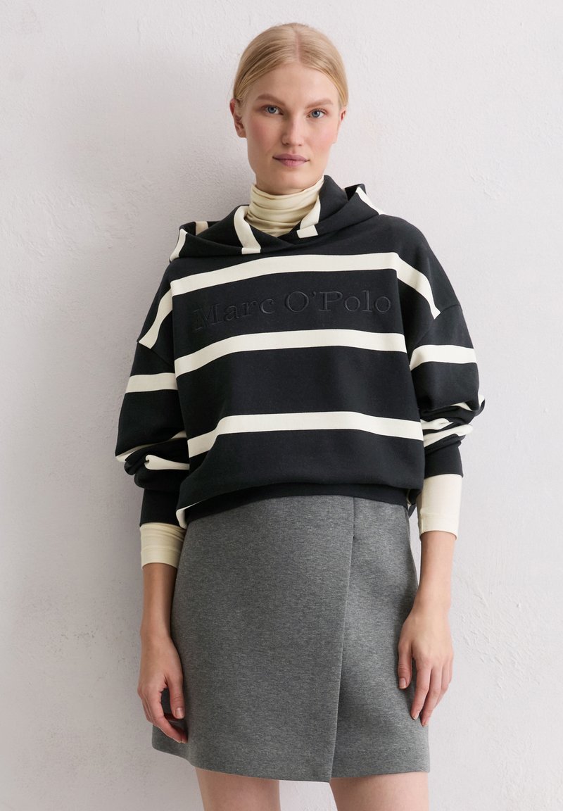 Black and white striped oversized hoodie with embossed "Marc O'Polo," paired with a gray mini skirt. Cotton blend fabric, relaxed fit.